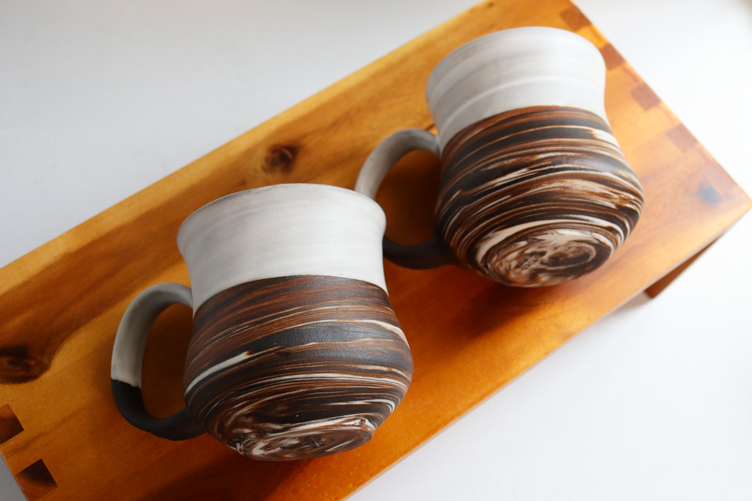Dark brown stoneware and porcelain marbled mugs with satin white glaze
