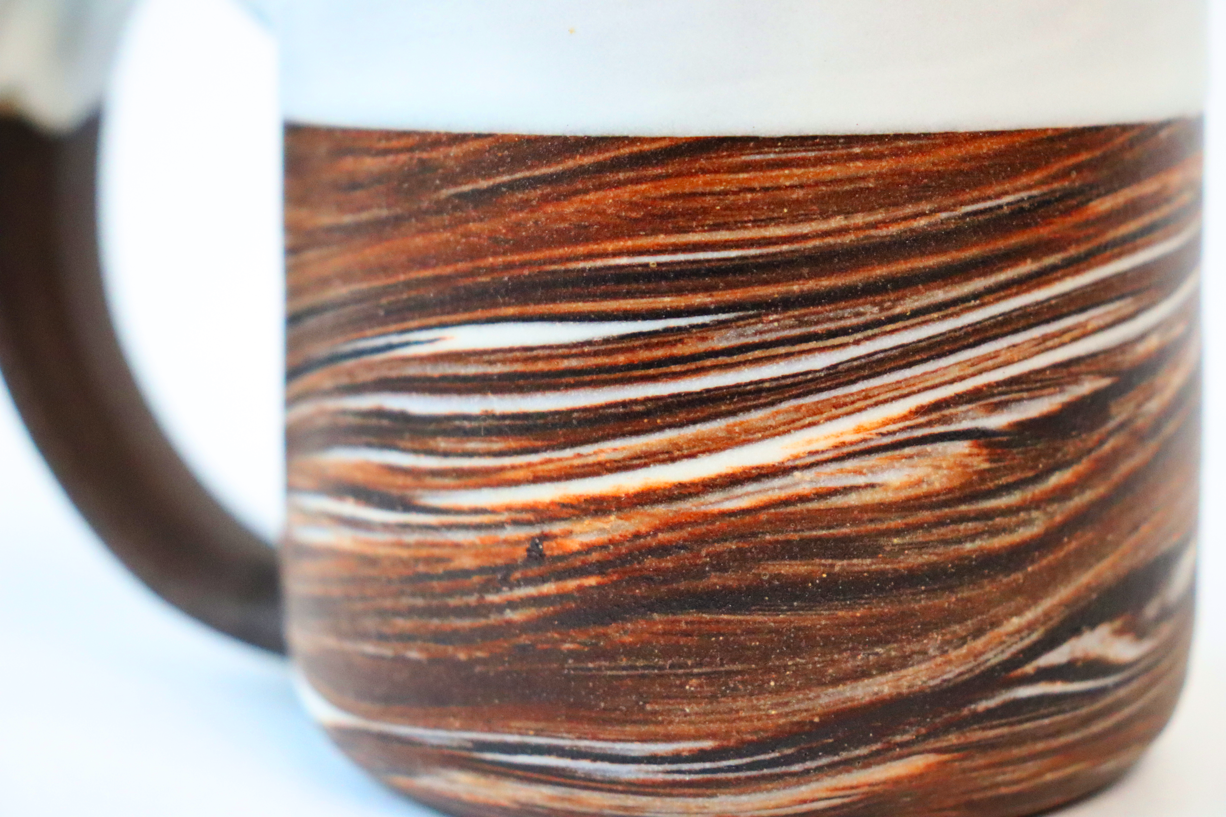 Dark brown stoneware and porcelain marbled mug with satin white glaze close up