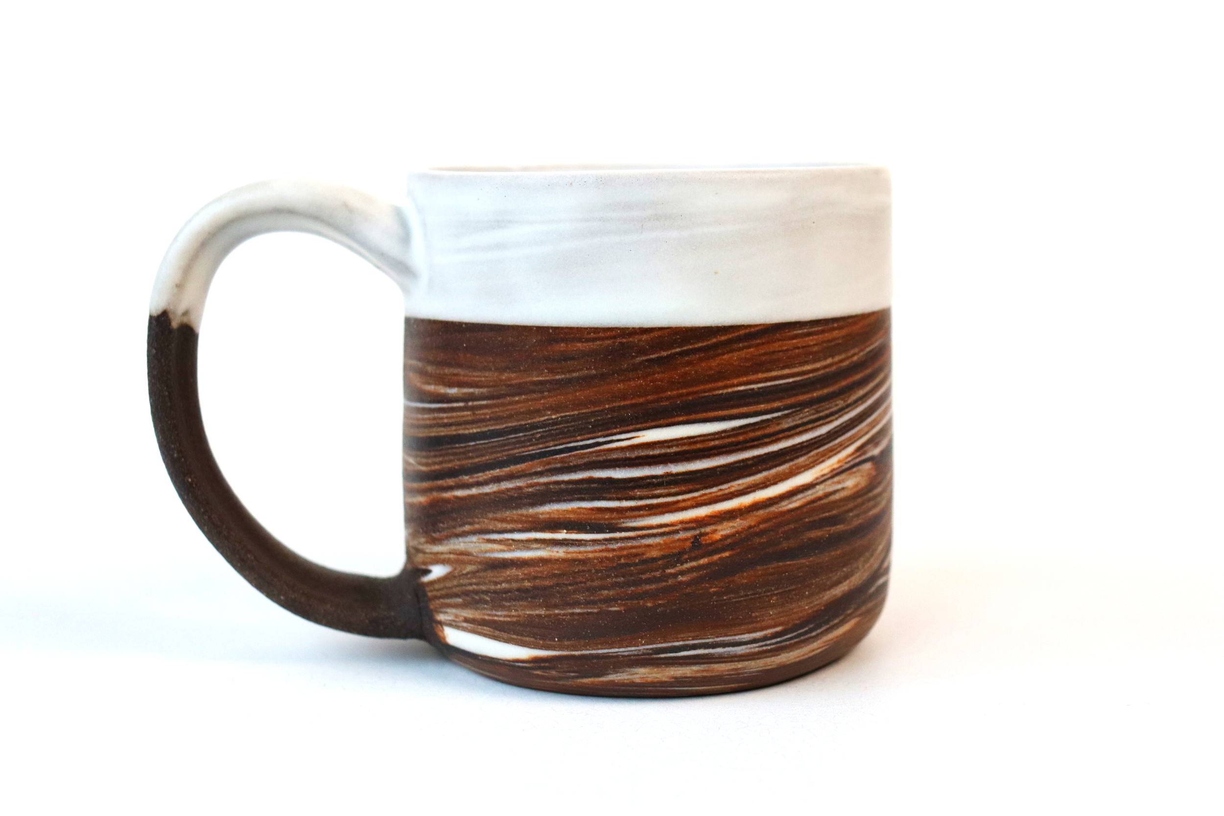 Dark brown stoneware and porcelain marbled mug with satin white glaze sitting on white surface