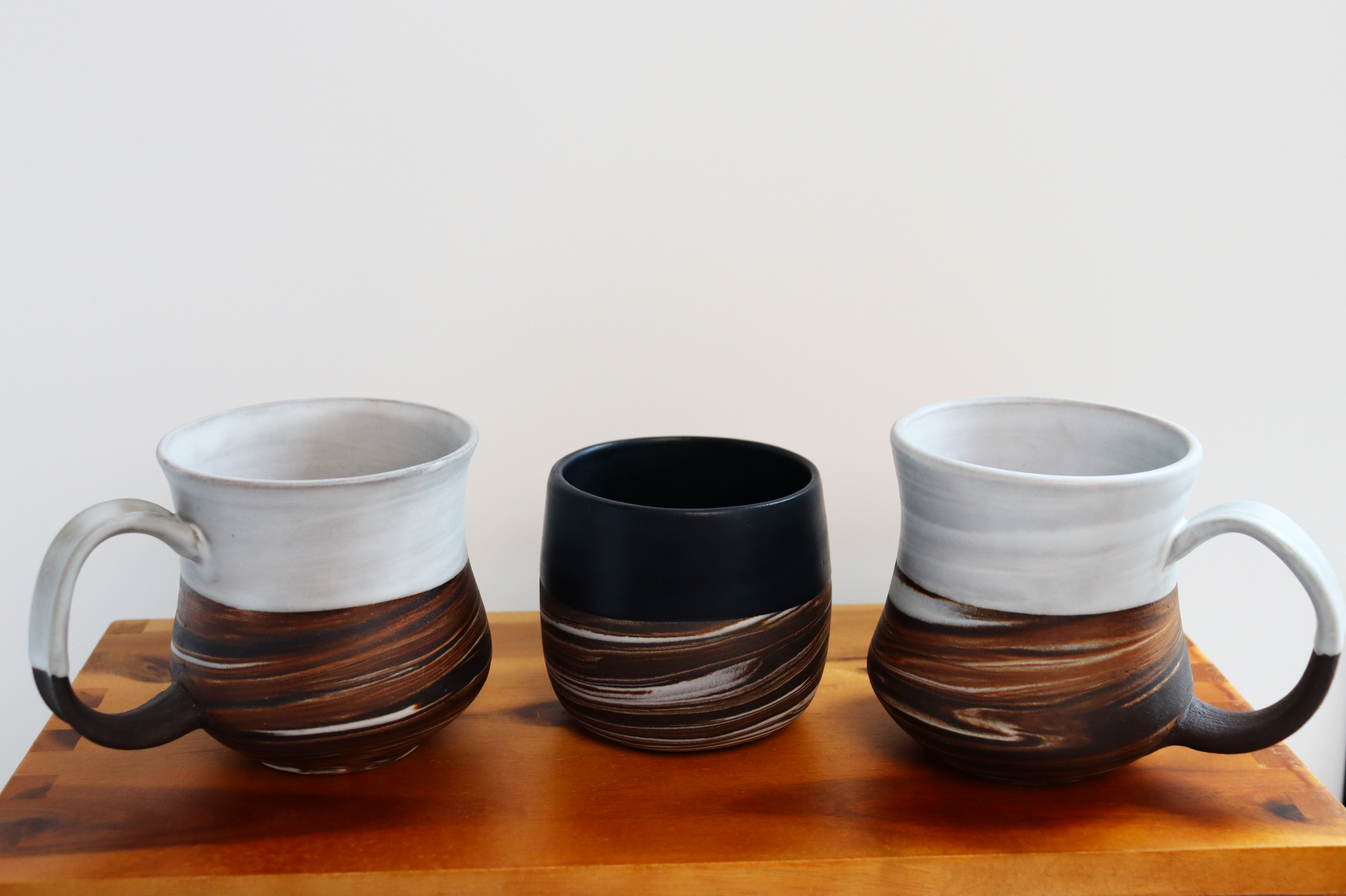 Dark brown stoneware and porcelain marbled mugs and tumblers with satin white or black glaze