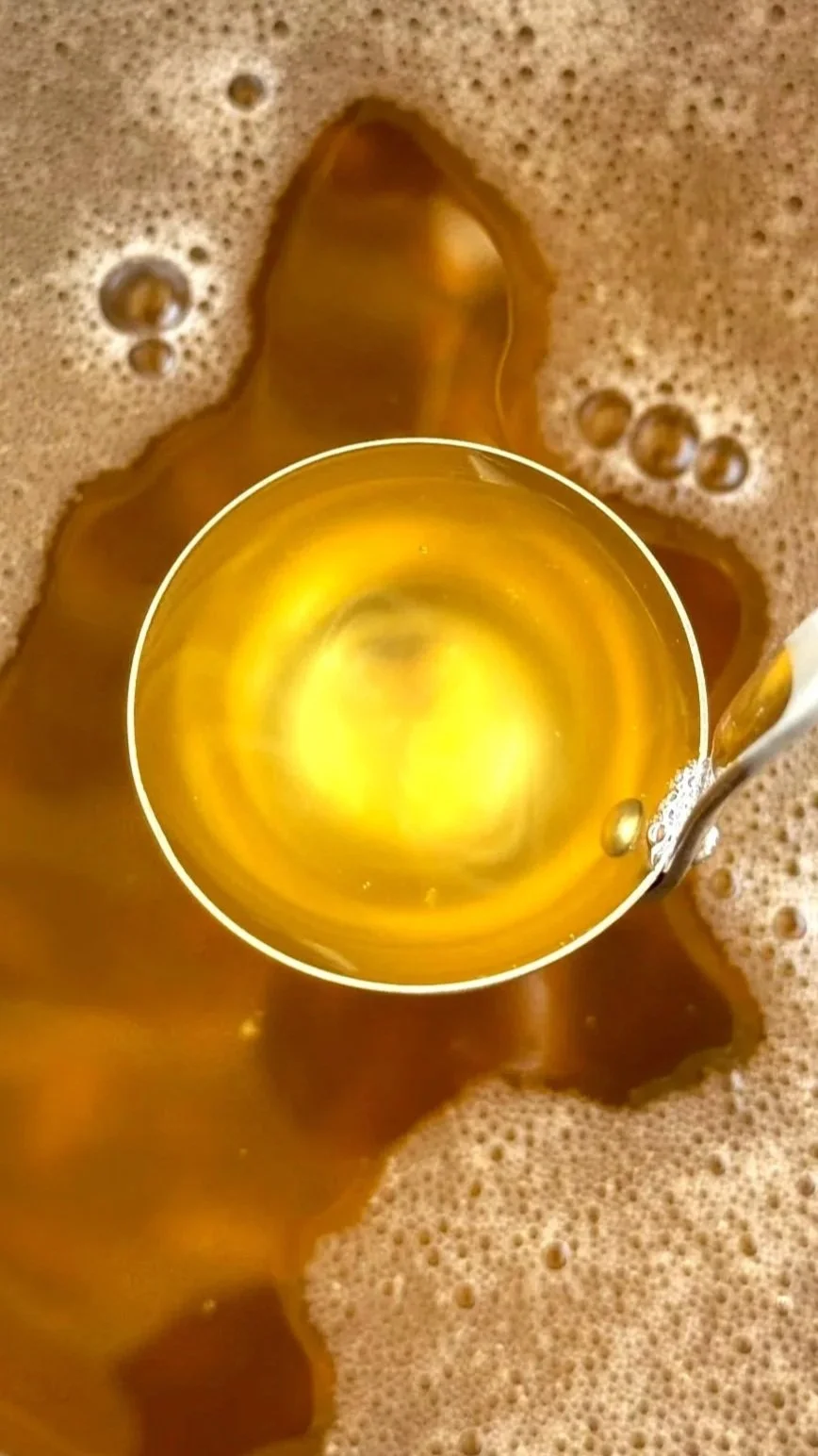 Close-up of a beer glass being filled with beer, surrounded by foam and bubbles.