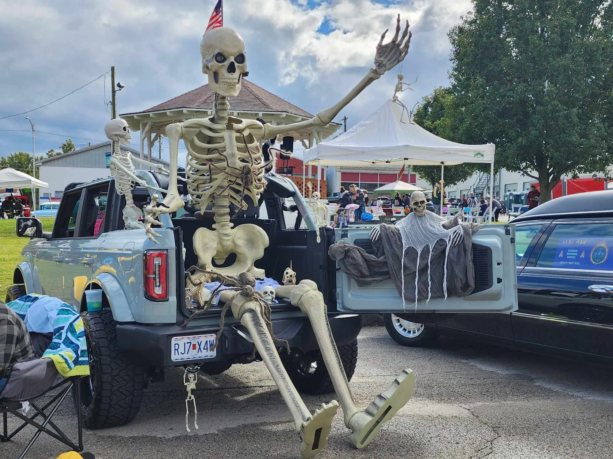 Decorated truck with large skeletons, fake cobwebs, and Halloween decorations at a festival