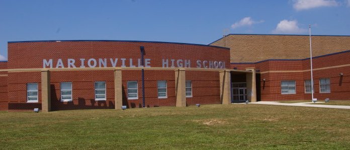 Marionville High School building with a brick facade, grassy lawn in front, and a clear blue sky.