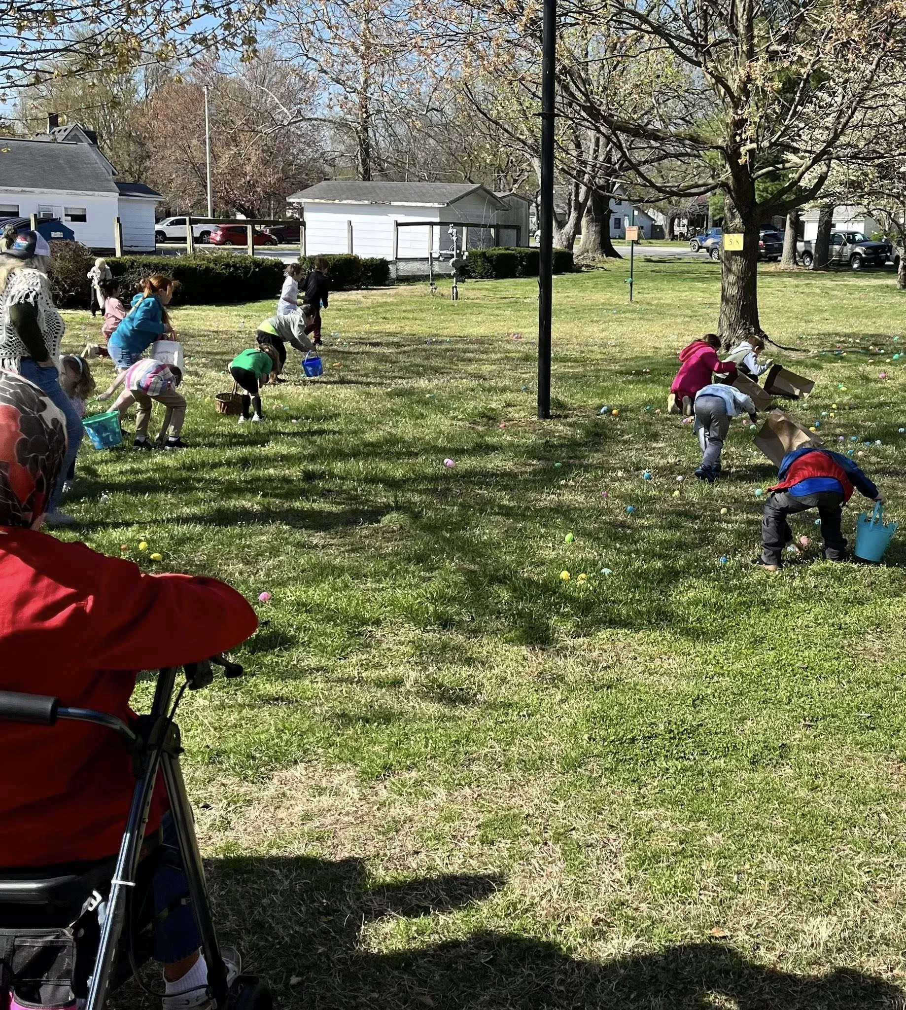 Children participating in an Easter egg hunt in a park on a sunny day, collecting colorful eggs scattered on the grass.