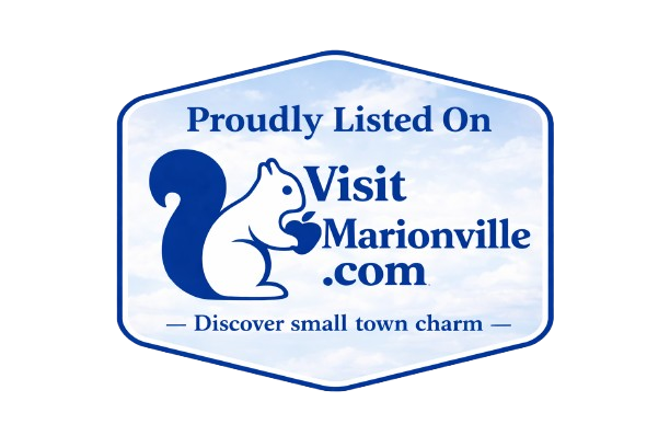A sign with a blue sky background that reads "Proudly Listed On VisitMarionville.com - Discover small town charm," featuring a squirrel holding an acorn.