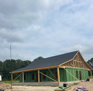 Construction site with a partially built prefab house, roofed by Patrick and sons.