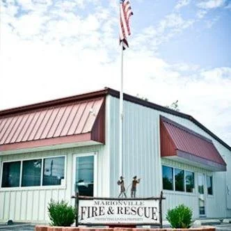 Marionville Fire & Rescue building with American flag on flagpole and children statues in front