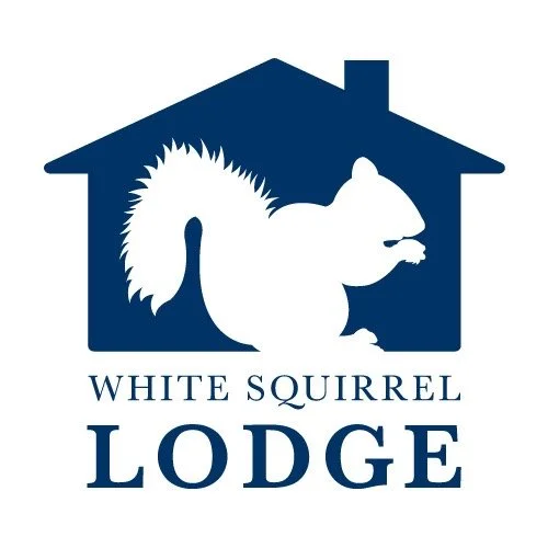 Logo of White Squirrel Lodge featuring a white squirrel inside a blue house silhouette with text below.