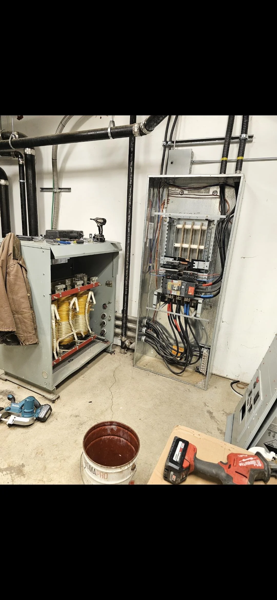 Electrical panel and components being installed or repaired, with tools and equipment on the floor.