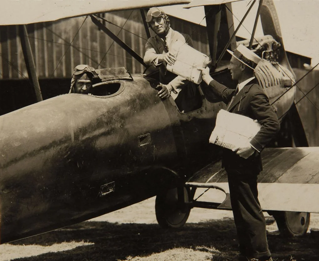 Walter O. Runcie receiving a package on a vintage biplane.
