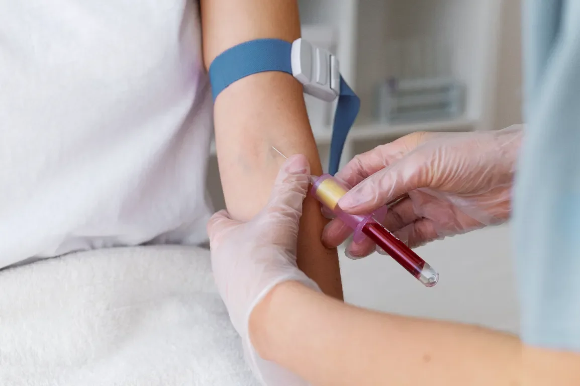 Medical professional drawing blood from a patient's arm with a syringe and collection tube