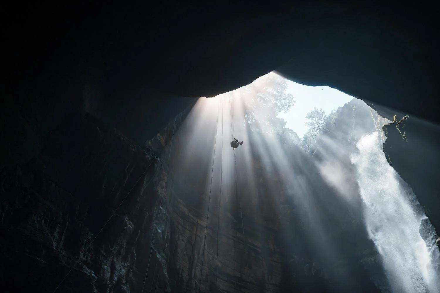 Climber descending into a cave toward light symbolizing courage and navigating uncertainty after genetic cancer risk