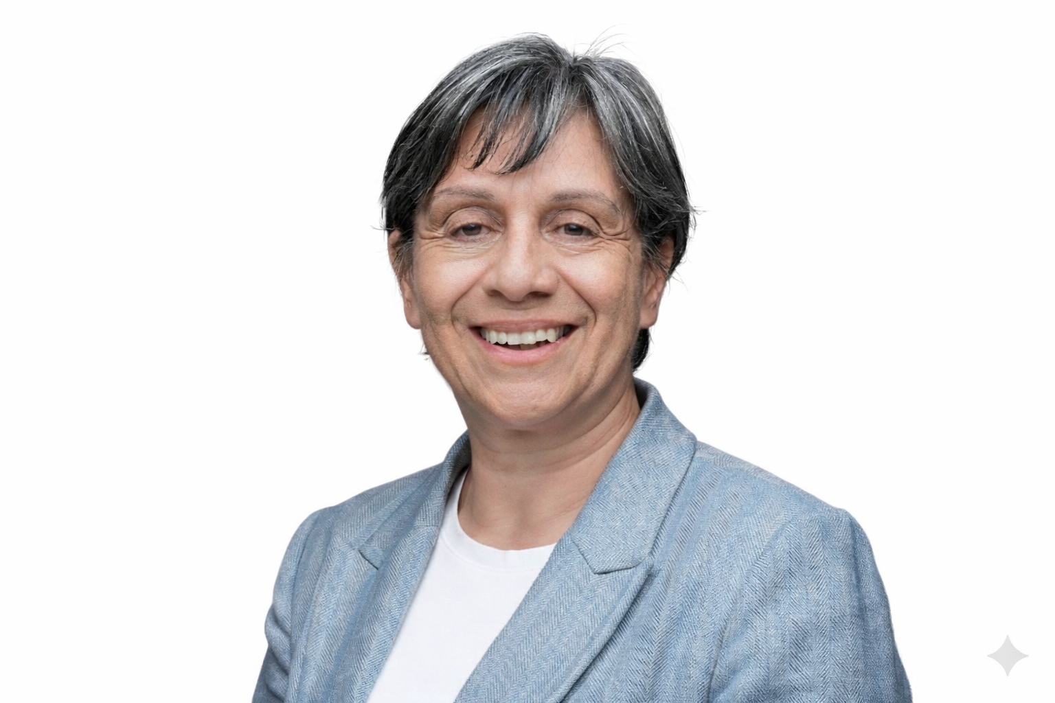 Portrait of a smiling middle-aged woman with short dark gray hair, wearing a light blue blazer over a white top, against a plain white background.