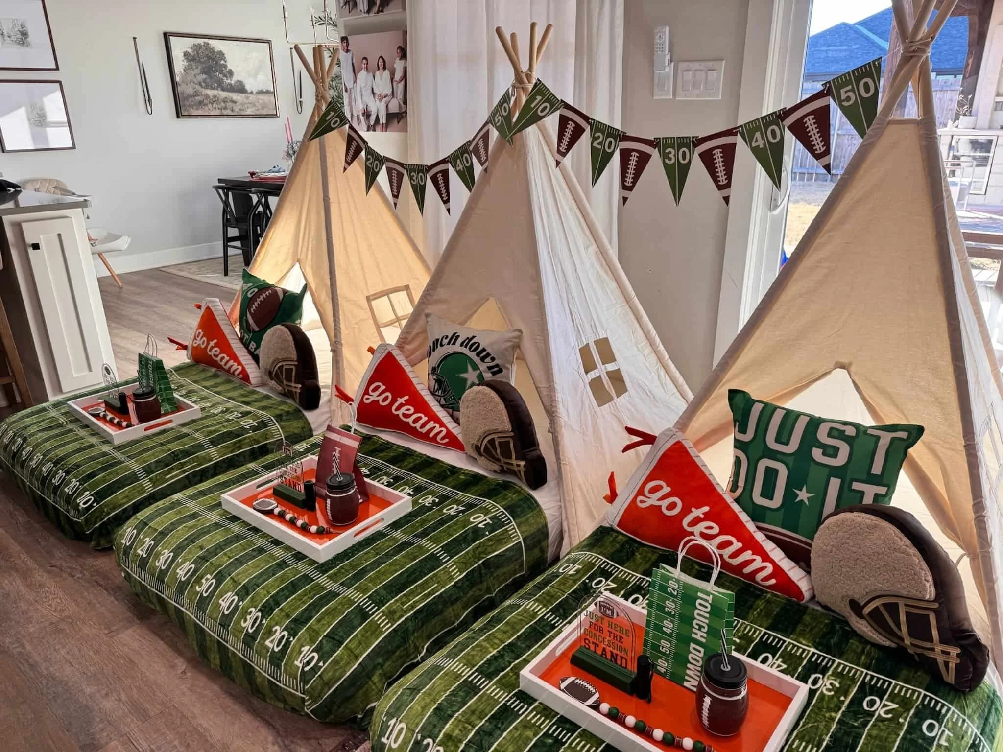 Three indoor tents with football-themed bedding, pillows, trays, and decorations, arranged for a kids’ sleepover party.