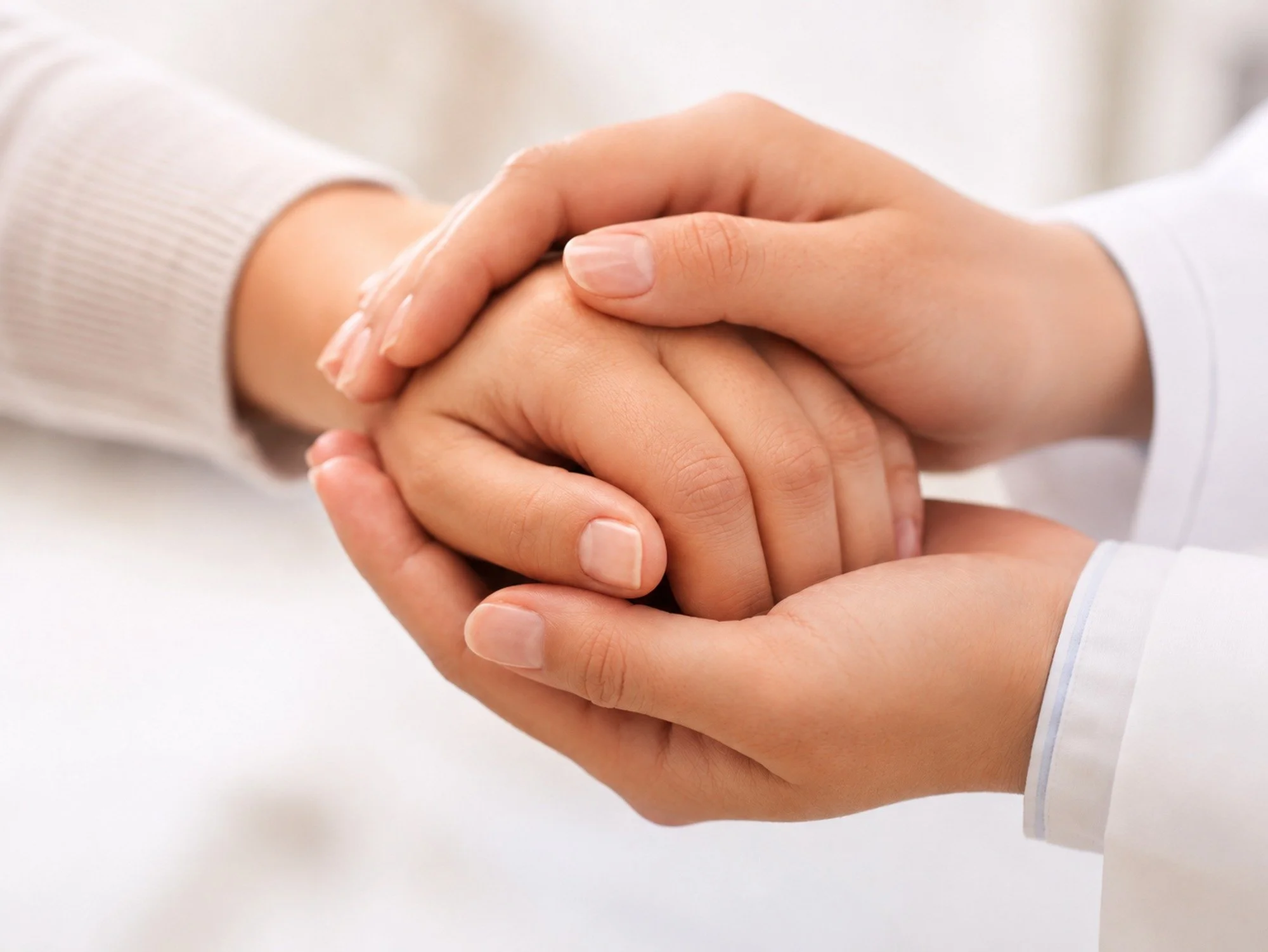 Two hands gently clasped together in a supportive gesture.