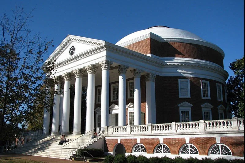 The White House with classical columns and a dome, set against a clear blue sky.