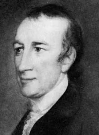 Black and white portrait of a man with short hair, wearing a dark coat and white shirt, looking to the side.