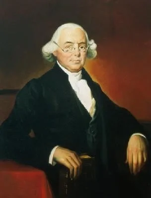 Portrait of George Washington in formal attire with white wig, black coat, and white shirt, sitting against a dark background.