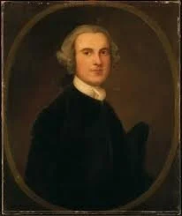Painting of a young man with light-colored hair in a dark suit, set in an oval frame.