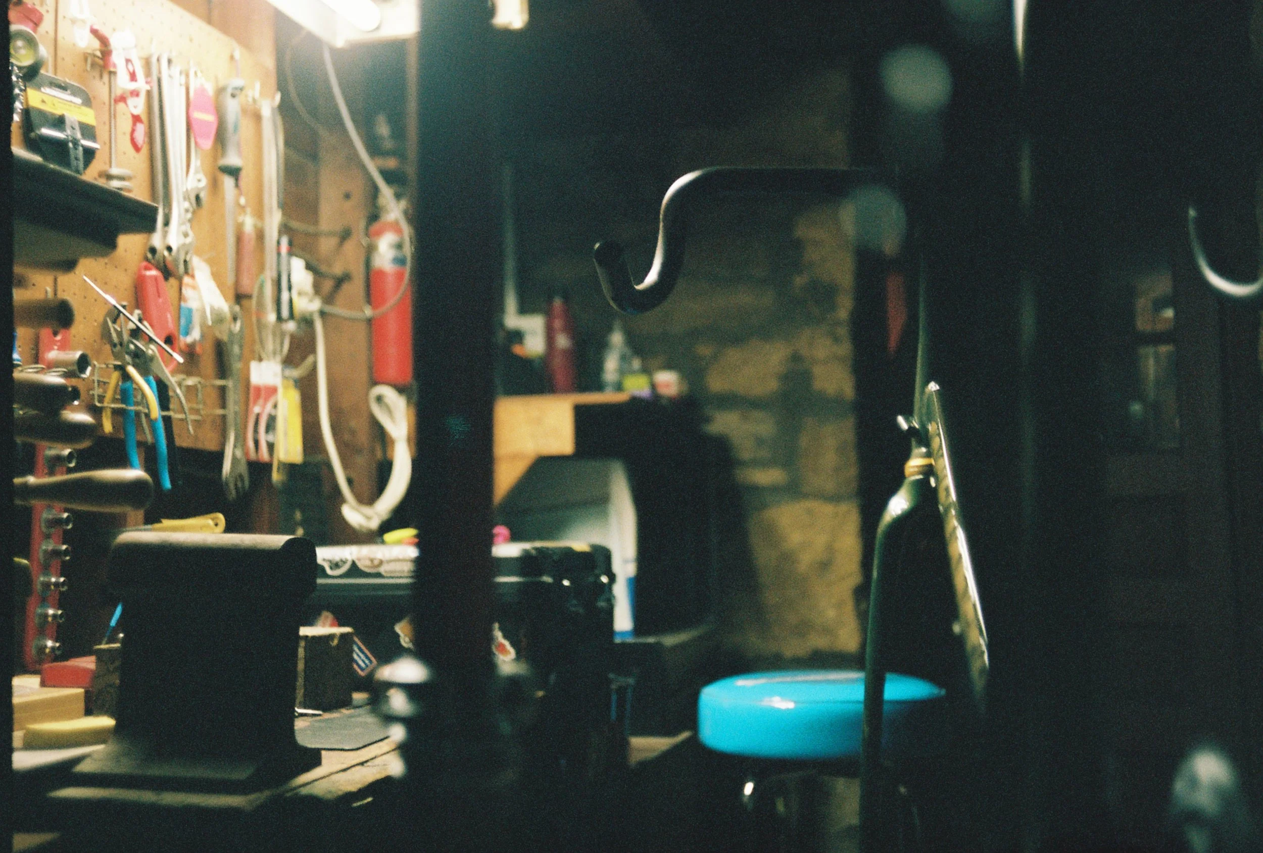 A bare bicycle frame hanging in a basement repair station.
