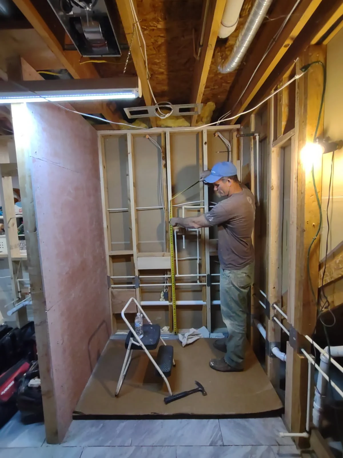 Lucid's founder Montgomery Gray framing out a basement with plumbing and electrical.