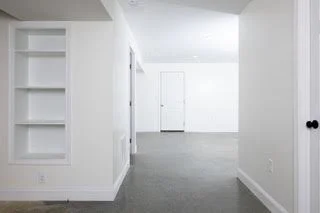 Empty white room with built-in shelves and a closed door