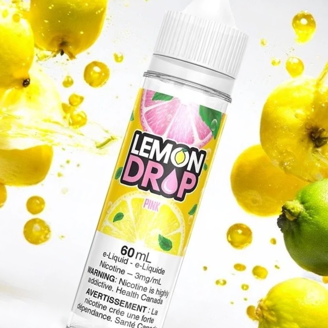 A 60ml bottle of Lemon Drop pink flavored e-liquid with lemon and lime slices on the label, surrounded by yellow and green apples and lemon juice splashes.