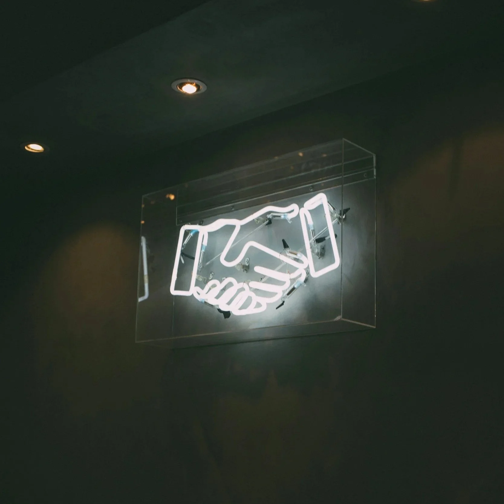Neon sign depicting a handshake inside a transparent box