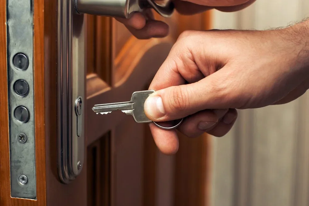 Person inserting a key into a door lock.