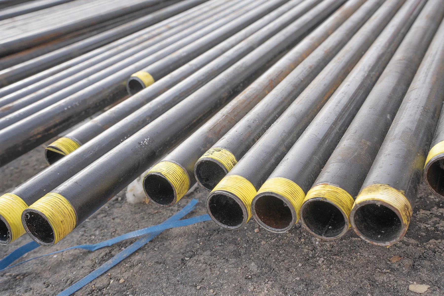 Metal piping pipes with yellow safety caps laid on the ground.