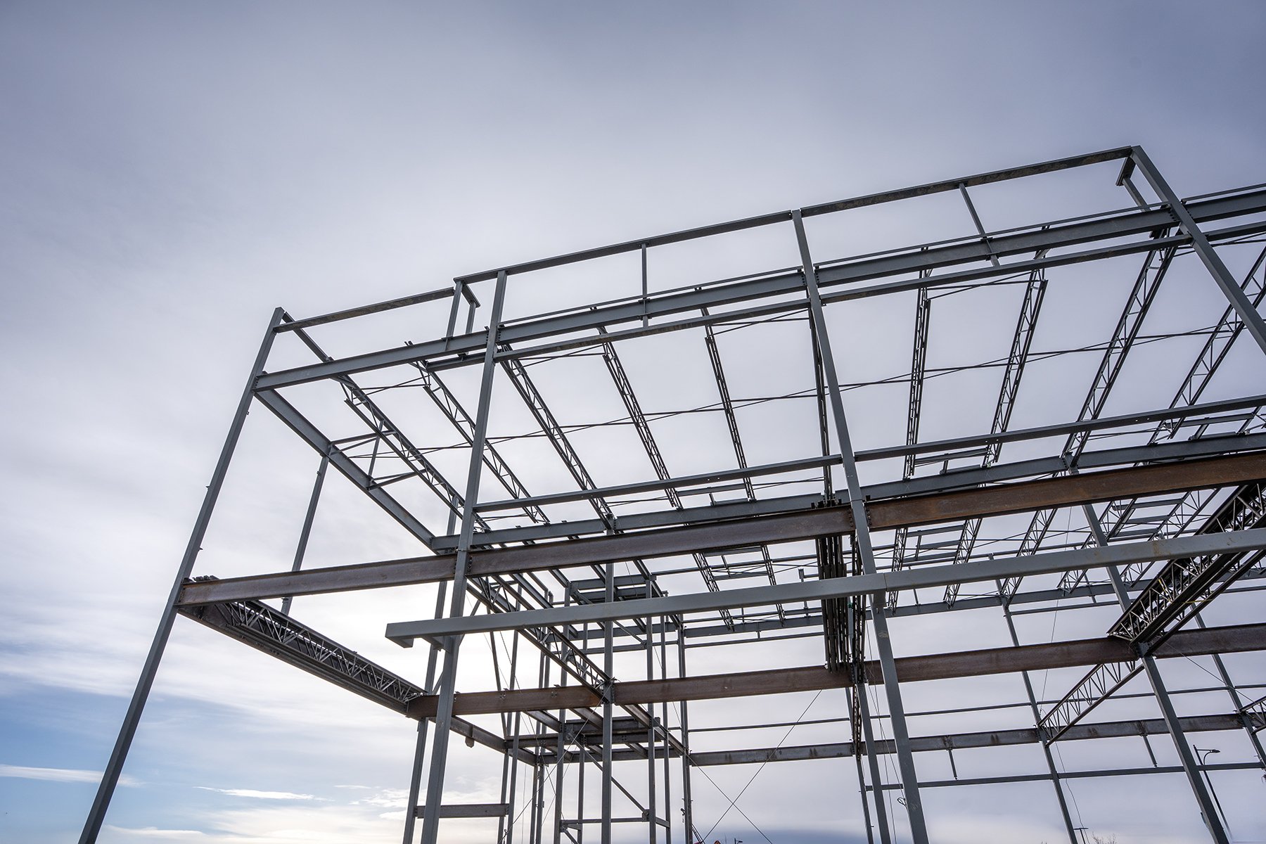 Steel framework of a building under construction against a cloudy sky.