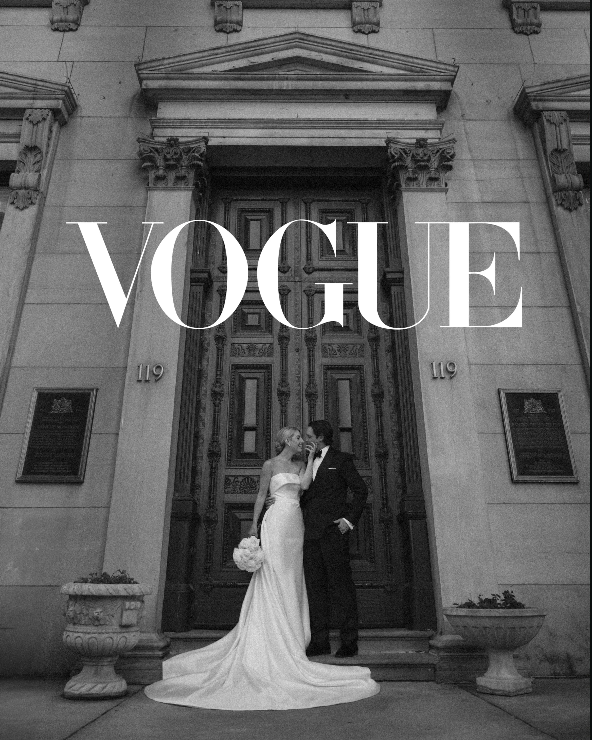 Black and white photo of a bride and groom standing in front of a large, ornate door on a building, with the Vogue logo overlaying the image.