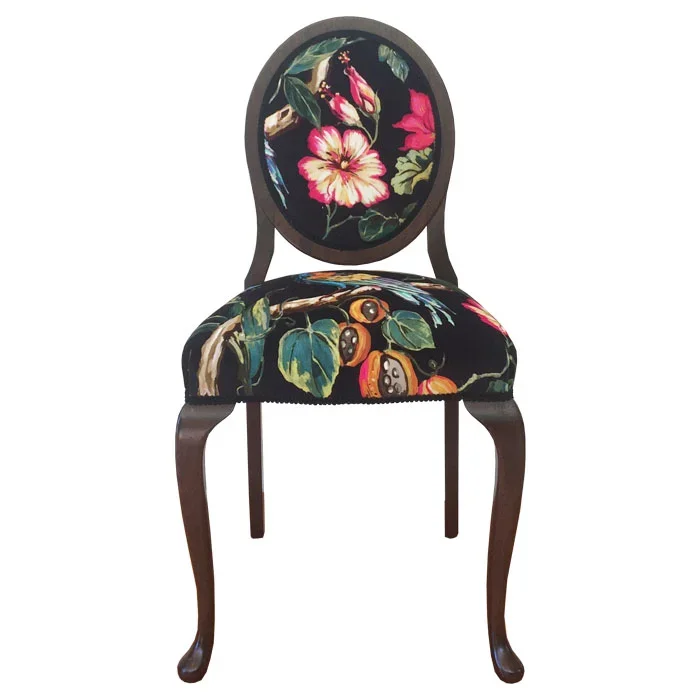 A wooden chair with a dark finish and curved legs, featuring a floral and vegetable pattern upholstery on the seat and backrest.