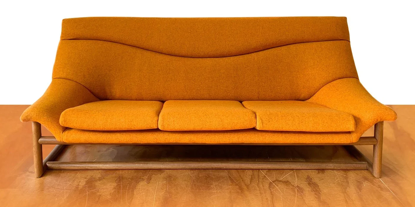 A mid-century modern orange upholstered sofa with wooden legs against a white background.