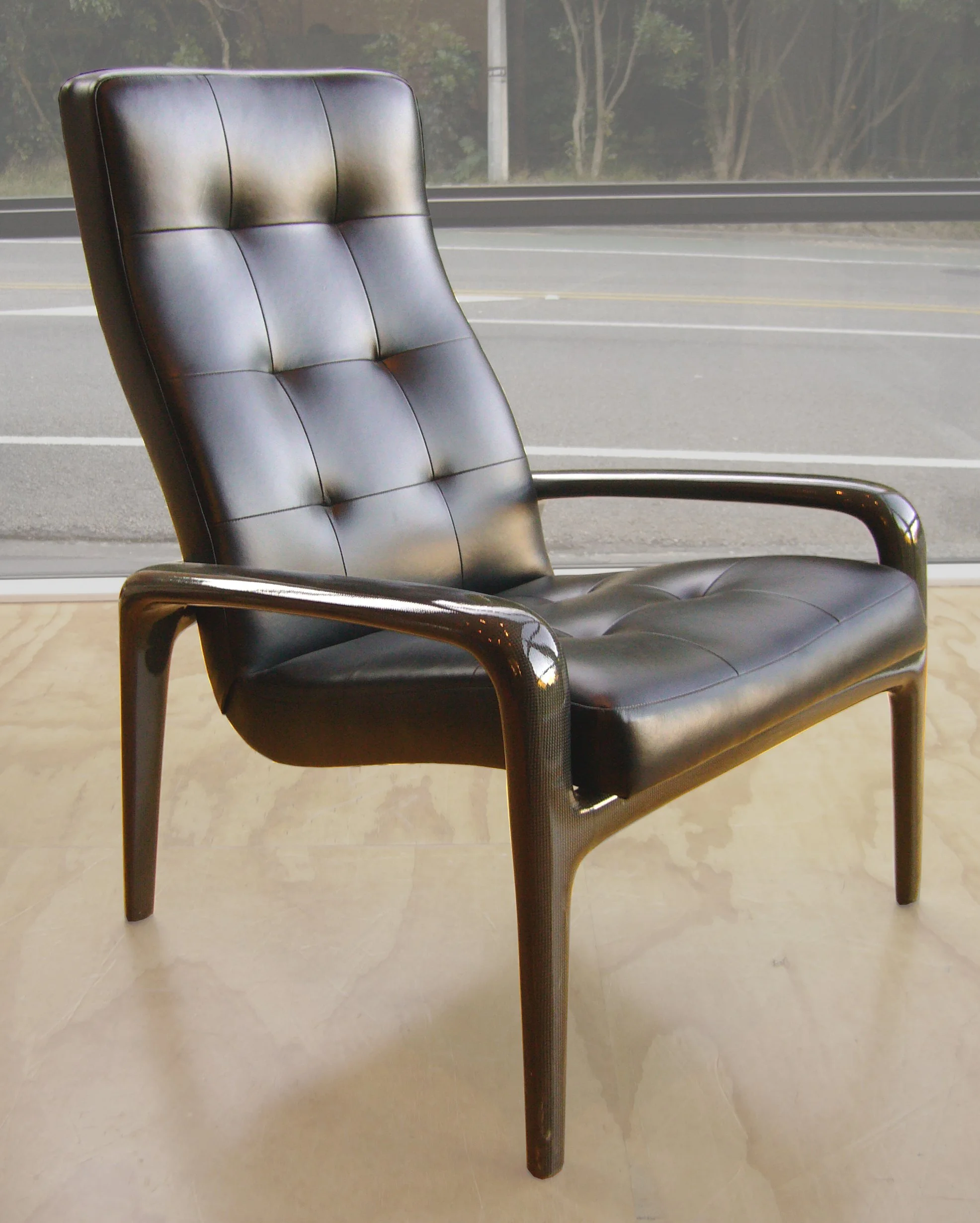 A custom leather and carbon fiber chair with a high backrest and tufted cushions.