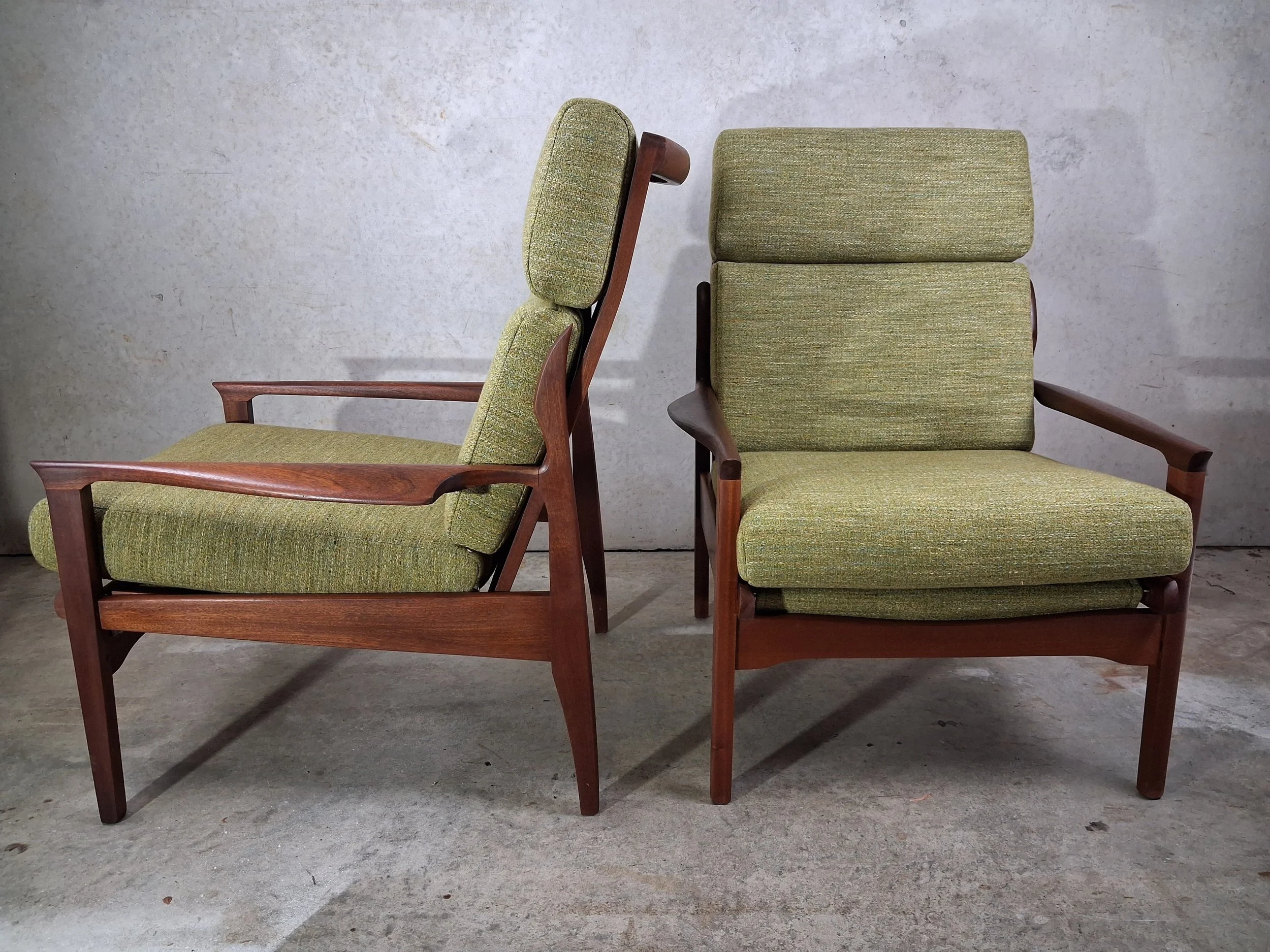 Two mid-century green upholstered armchairs with wooden frames, one shown from the side and the other from the front, placed against a plain wall.