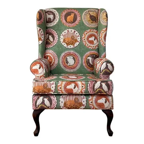 Upholstered armchair with a colorful pattern of various animal faces within circular borders.
