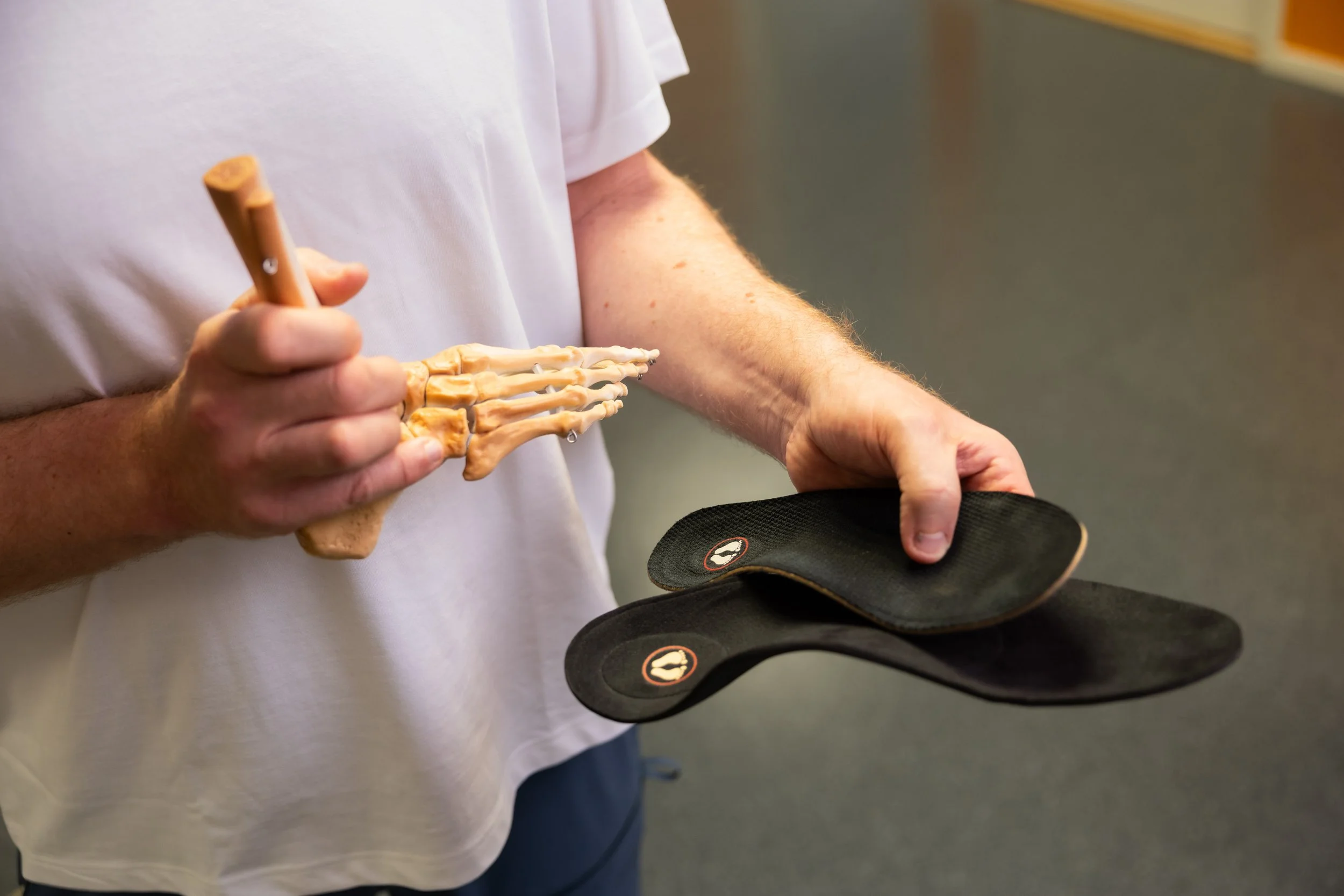 Fysioterapeut holder Supersole innleggssåle og anatomisk fotmodell ved Tromsø Fysioterapi