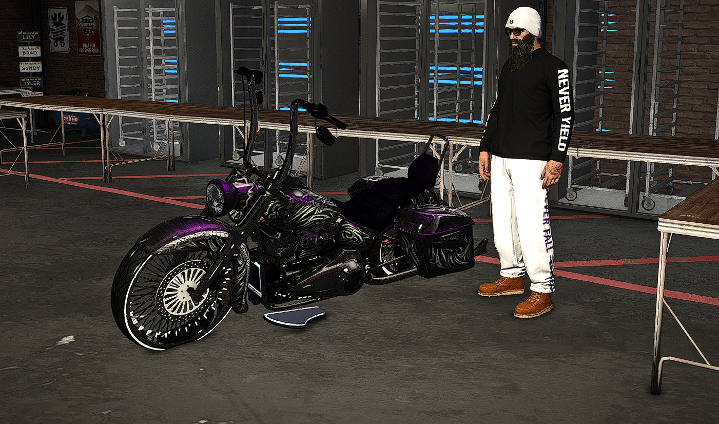Man with a beard, sunglasses, white helmet, black sweatshirt reading 'Never Mind' and white pants standing next to a custom black motorcycle with purple accents inside a garage or workshop.
