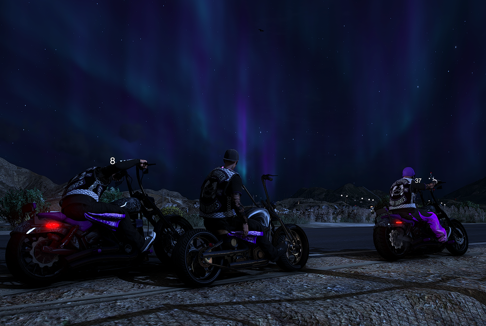 Three bikers in nighttime landscape watching northern lights in the sky.