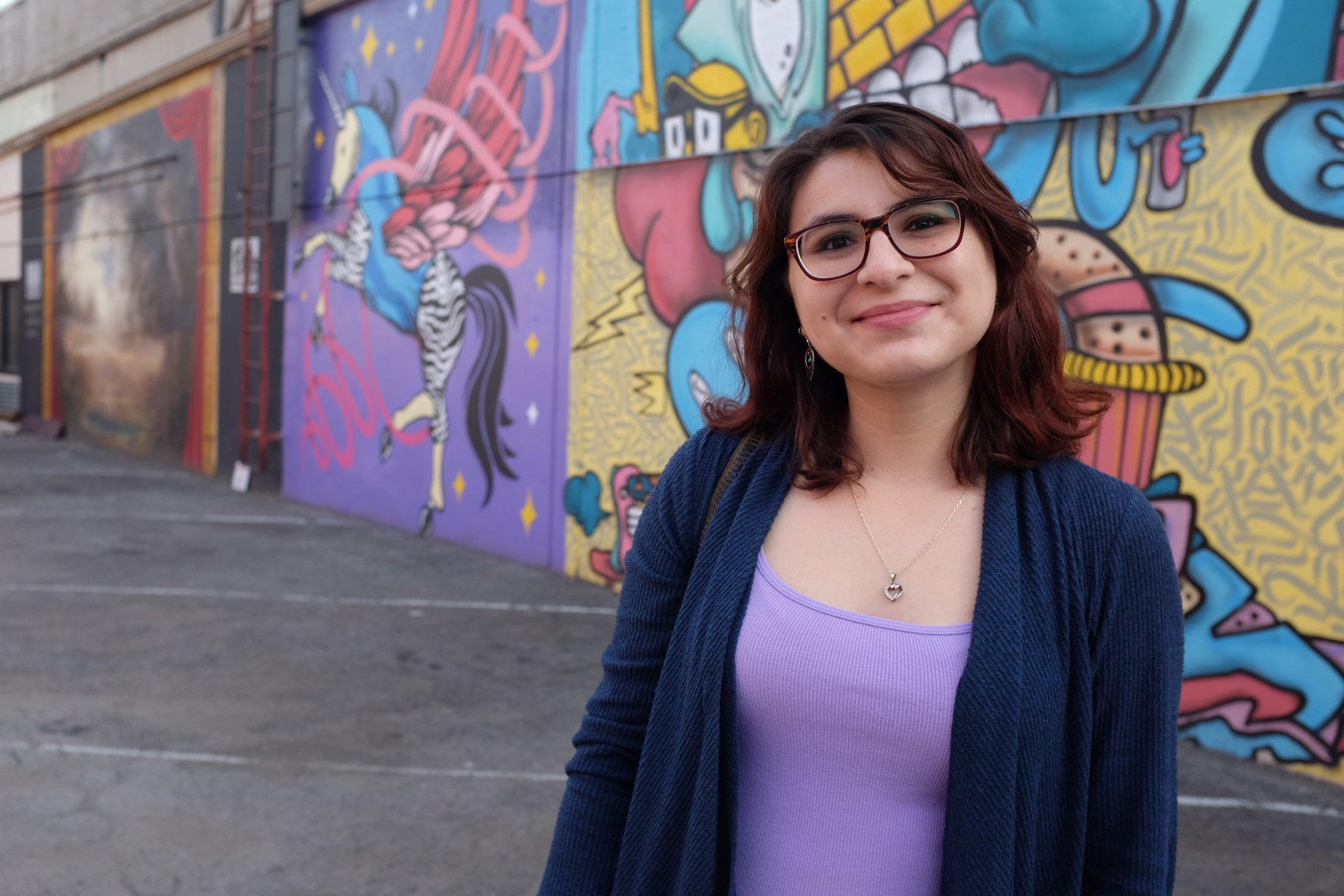 Profile picture of Laura Cueva with street art murals in the background.