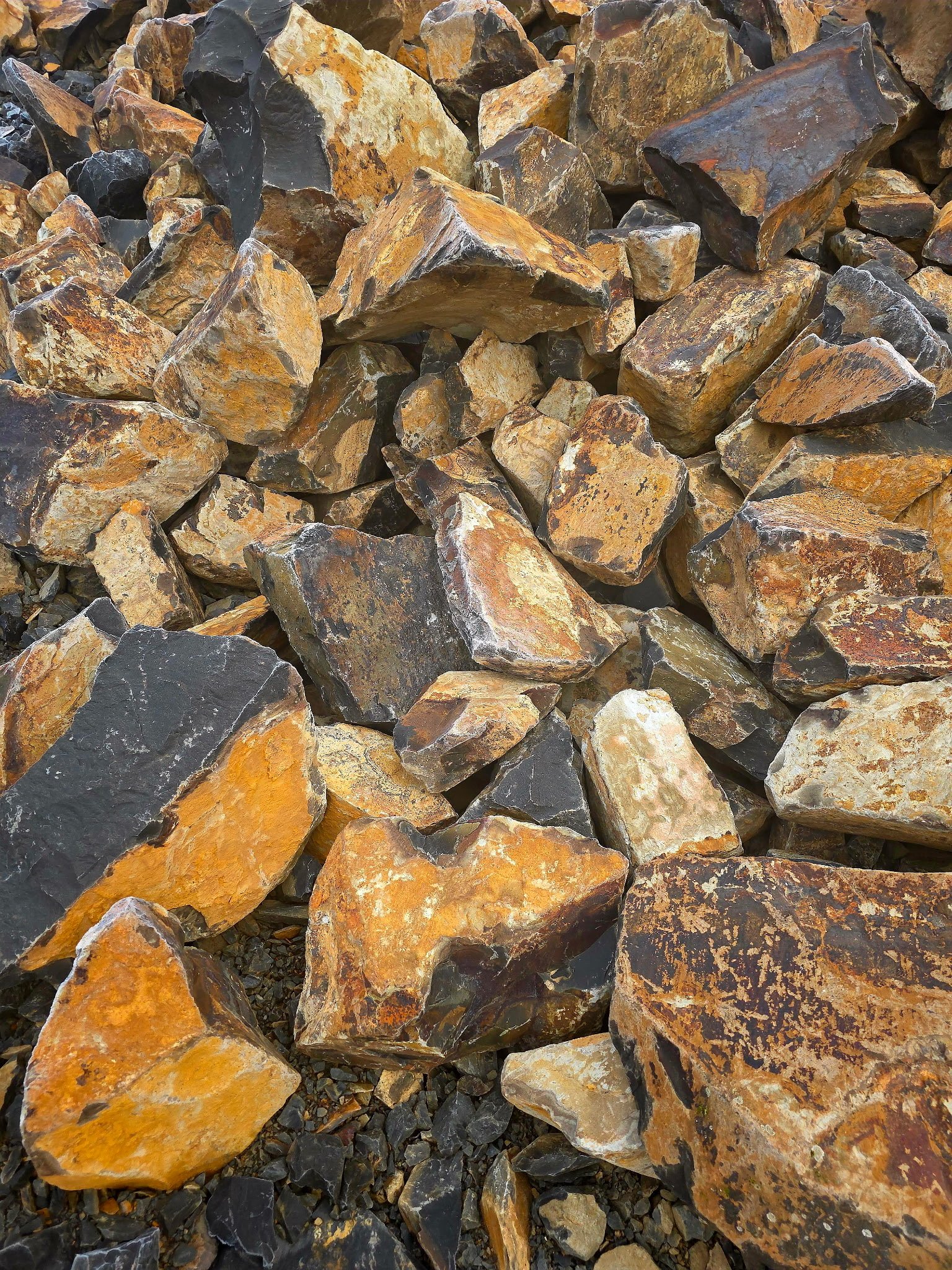 Pile of jagged rocks in shades of orange, brown, gray, and black.