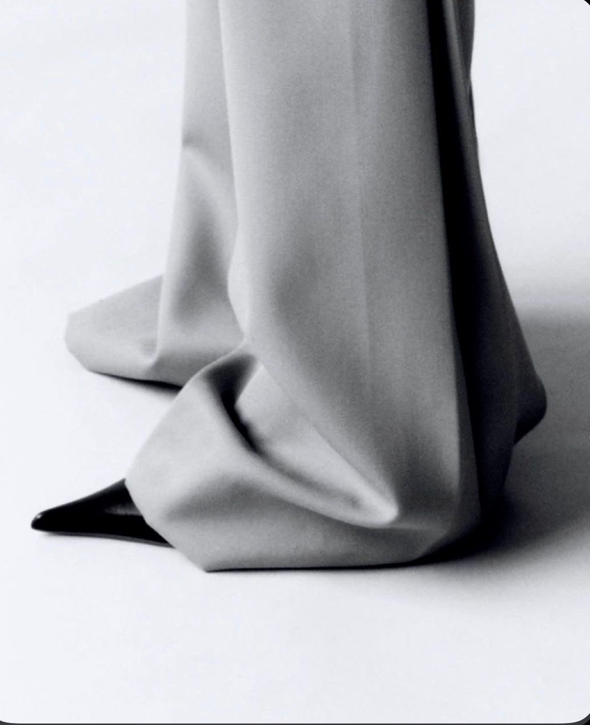 Close-up of crumpled metallic silver and black fabric on a white background.