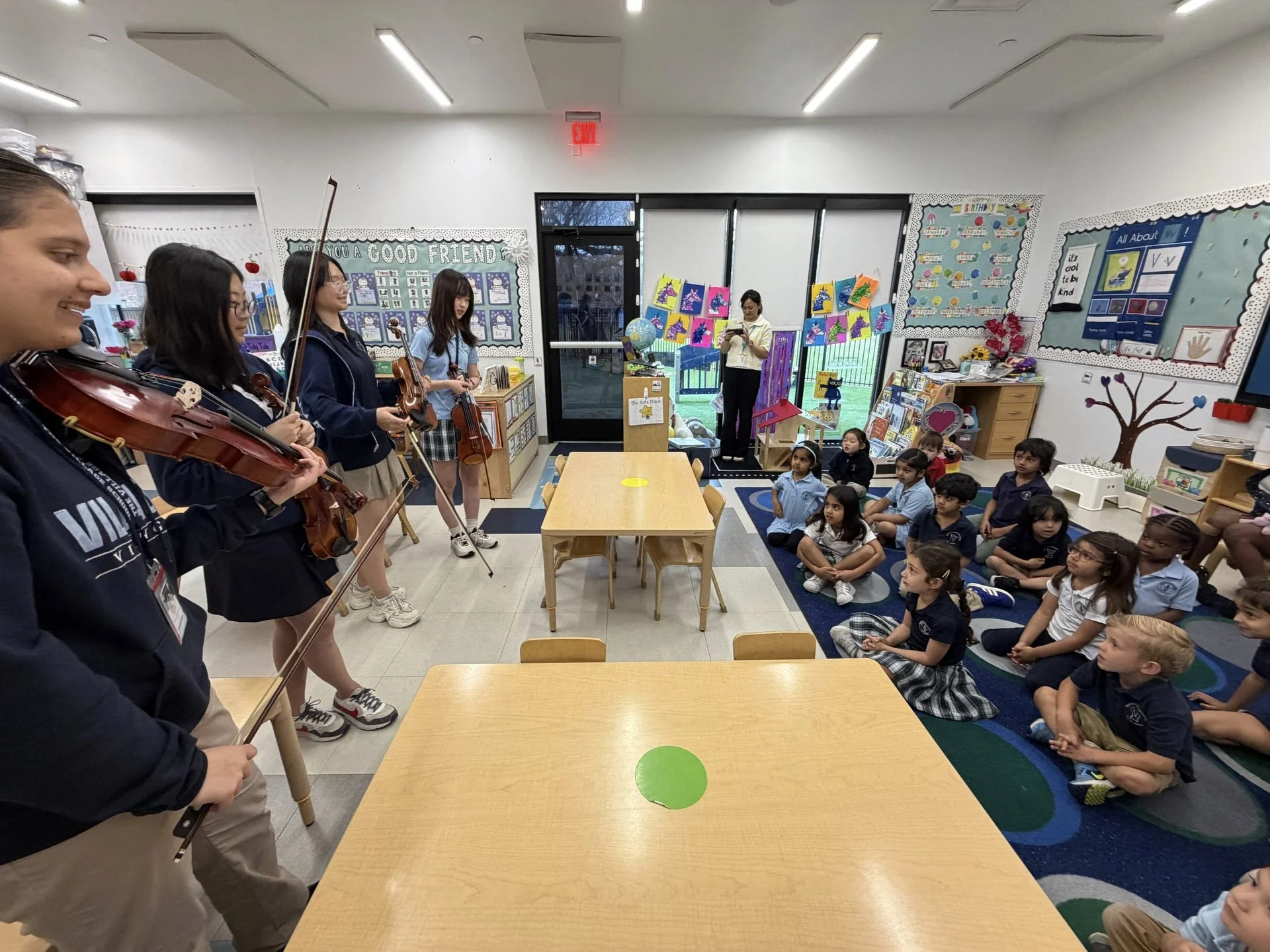 Village High School chamber orchestra students performing for elementary school children in classroom setting