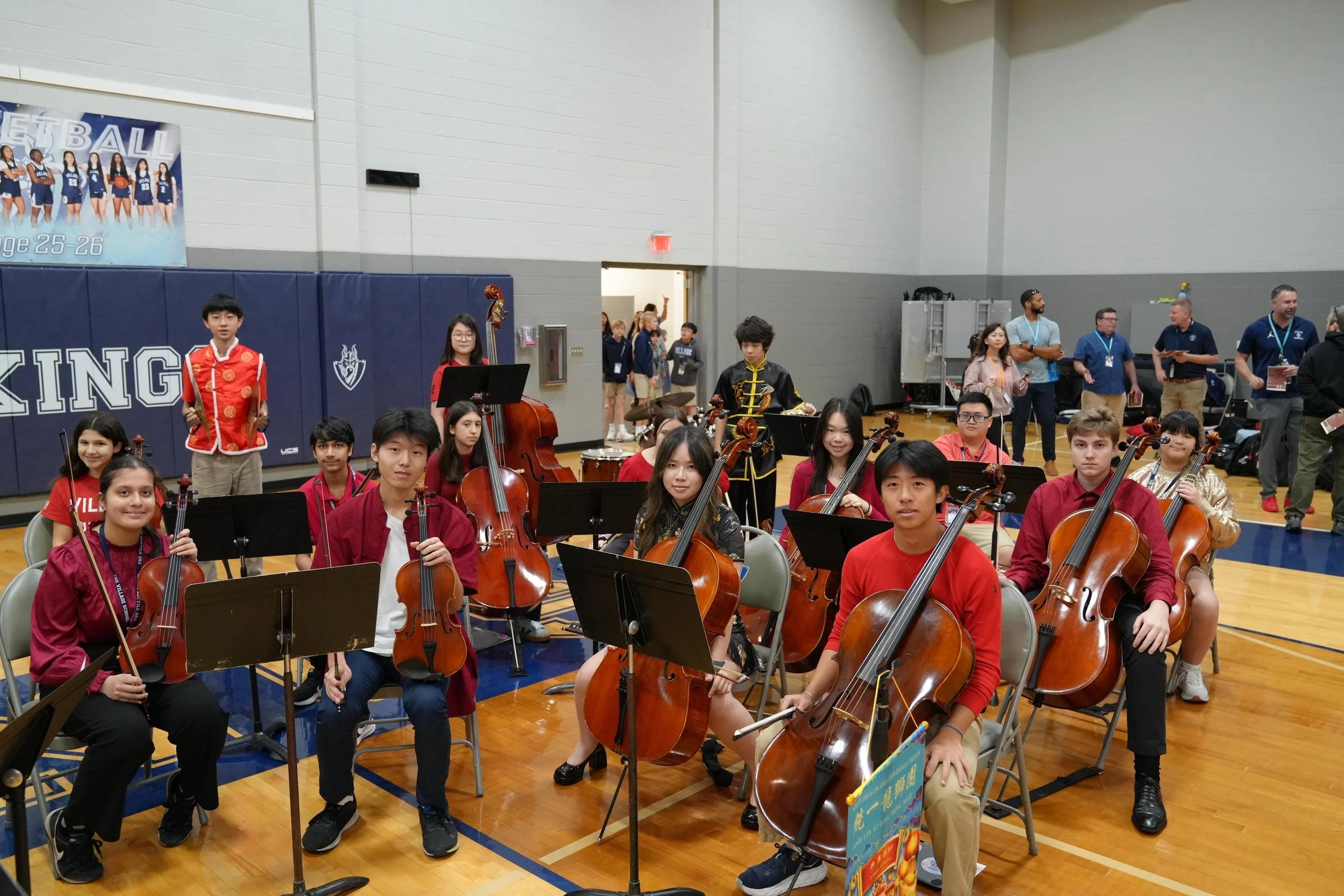 Village High School chamber orchestra rehearsing in school gymnasium with string instruments