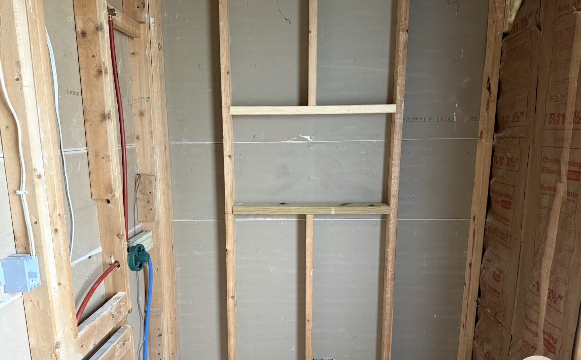 Interior of a building under construction with exposed wooden framing and electrical wiring.