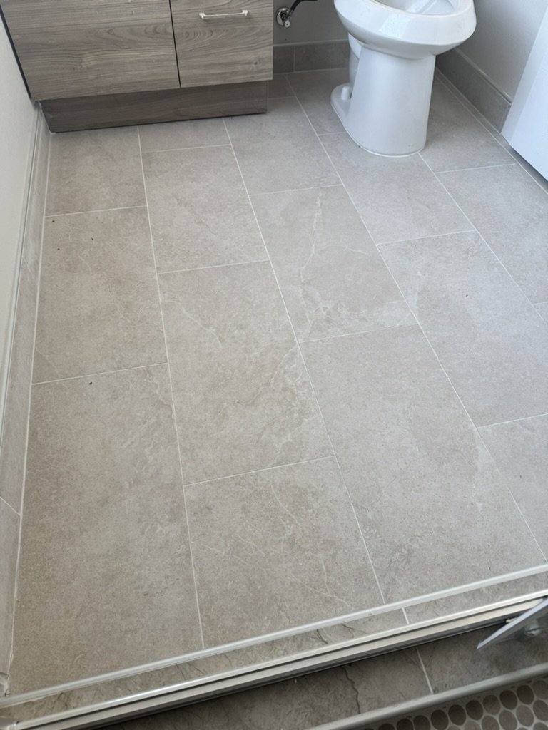 Bathroom with beige tiled floor, a wooden cabinet, and a white toilet.