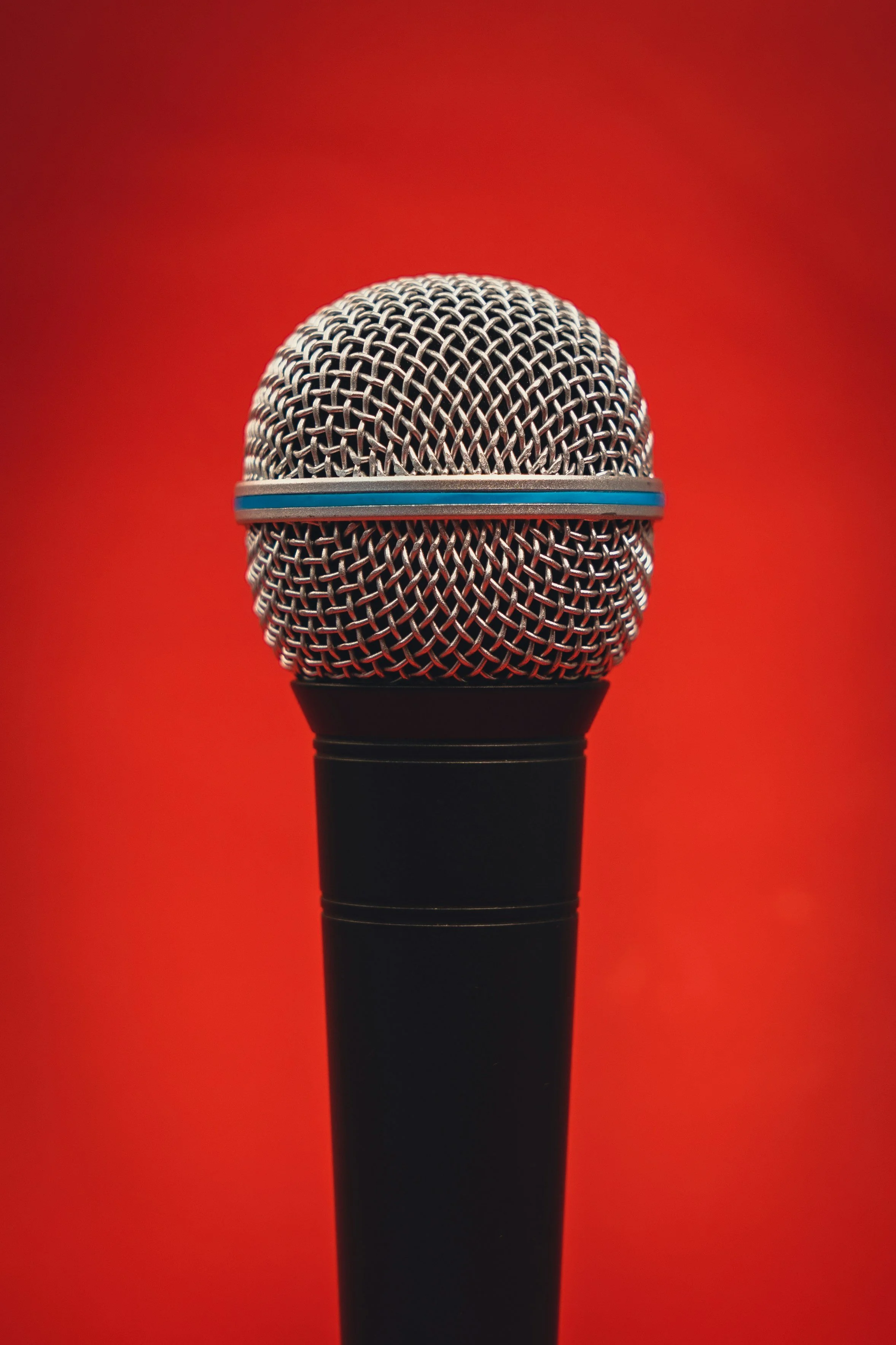 Close-up of a microphone with a red background.