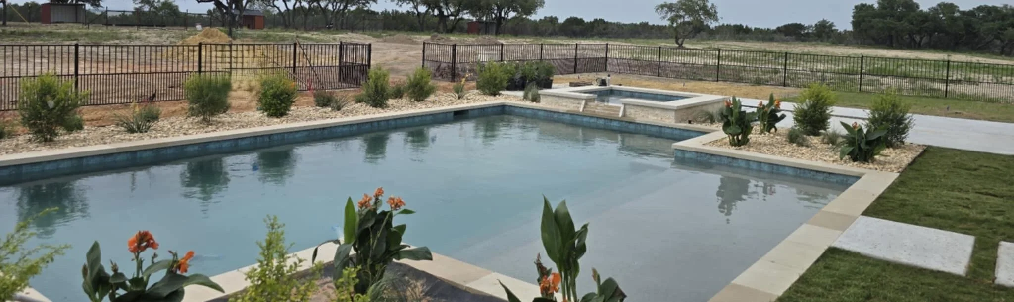 A backyard with a swimming pool and hot tub surrounded by a stone deck, design.  best of. custom pools.  texas. best of hood county. family owned. quality. luxury. ultimate custom pools. fort worth. honest. great reviews.trusted. 