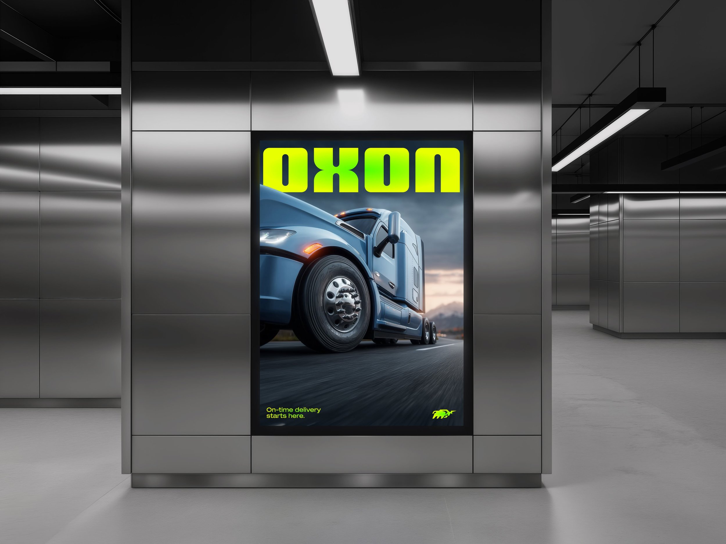 View of an elevator interior leading to a garage with a large truck parked outside, visible through the open elevator door. The elevator has metallic walls and modern lighting. There is a bright advertisement on the elevator wall showing a blue truck and text that reads "On-time delivery starts here" in yellow.